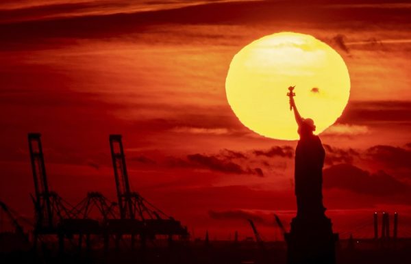 The sun sets behind the Statue of Liberty, Thursday, Nov. 17, 2022, in New York. (AP Photo/Julia Nikhinson)